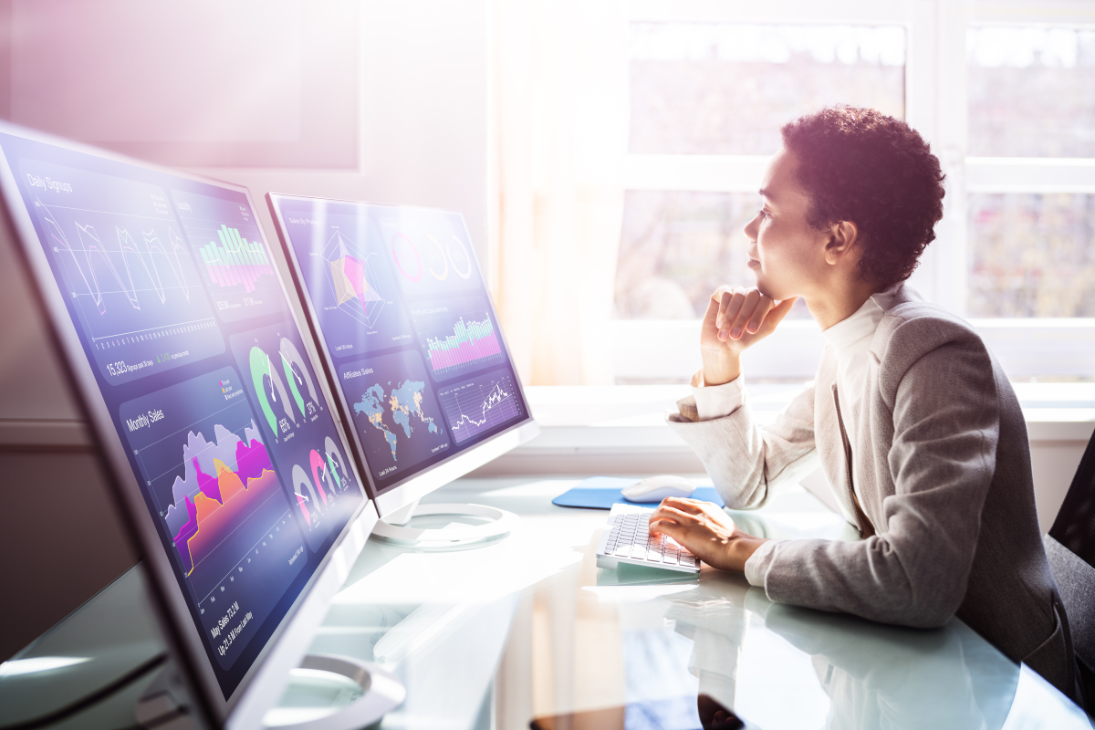 Analyst studying live data dashboards on multiple monitors
